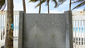 Un mur en béton muni de deux poignées métalliques, entouré d’une clôture blanche et de palmiers.