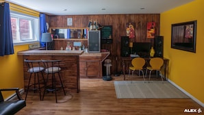 A compact kitchen with a bar area, wooden walls, and a yellow accent wall. - LITTLE PARADISE IN NEUVILLE, NATURE AND TRANQUILITY (Neuville)