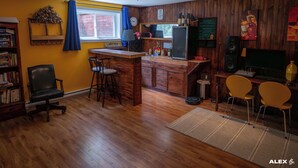 A compact kitchen with wooden cabinets, a refrigerator, a sink, and a bar area with stools. - LITTLE PARADISE IN NEUVILLE, NATURE AND TRANQUILITY (Neuville)