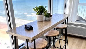 A balcony with a wooden table, two potted plants, and a pair of black headphones. - Beachfront & Oceanfront Views – Private Balcony (Daytona Beach)