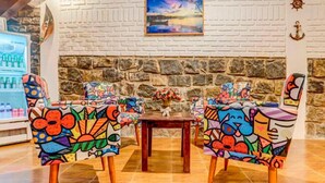 Un comedor con sillas coloridas y un fondo de pared de piedra.