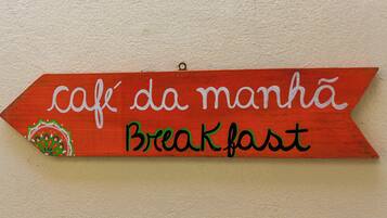 A wooden sign with the text "café da manhã Breakfast" and a decorative element.