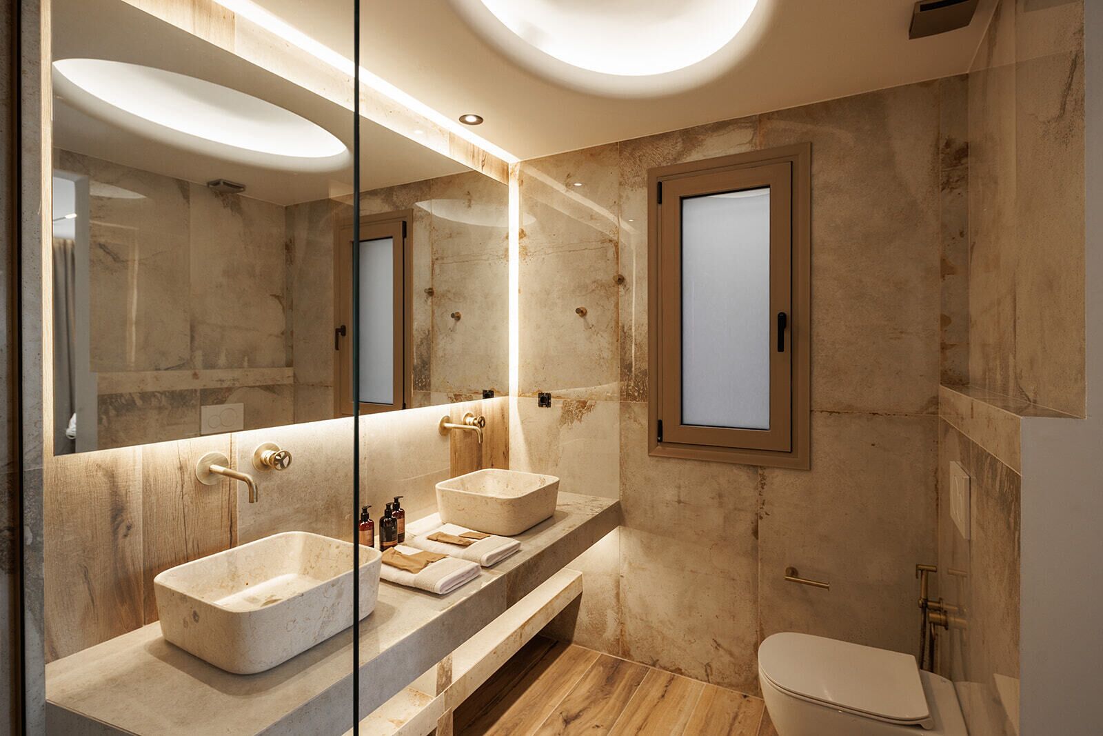 Ein modernes Badezimmer mit einem großen Spiegel, zwei Waschbecken und einer Toilette.