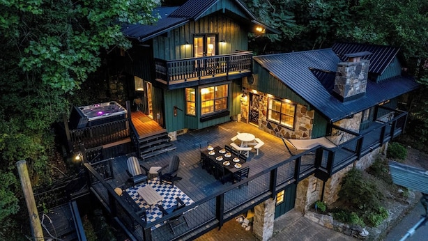Eine zweistöckige Holzhütte mit Balkon, Sitzbereich im Freien und Whirlpool.