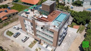 A multi-story building with a rooftop pool, multiple balconies, and a parking area.