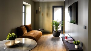 A modern living room with a brown sofa, a round glass table, and a potted plant.
