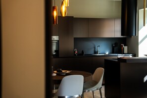 Una cocina moderna con armarios oscuros, un lavamanos de acero inoxidable y una mesa redonda con dos sillas.