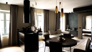 Eine moderne Küche mit einer zentralen Kochinsel, Essbereich mit rundem Tisch und Stühlen sowie Wohnbereich mit Sofa und Couchtisch.
