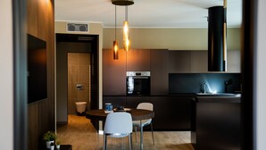 Eine moderne Küche mit Essbereich, ausgestattet mit Backofen, Kaffeemaschine und Pendelleuchten.
