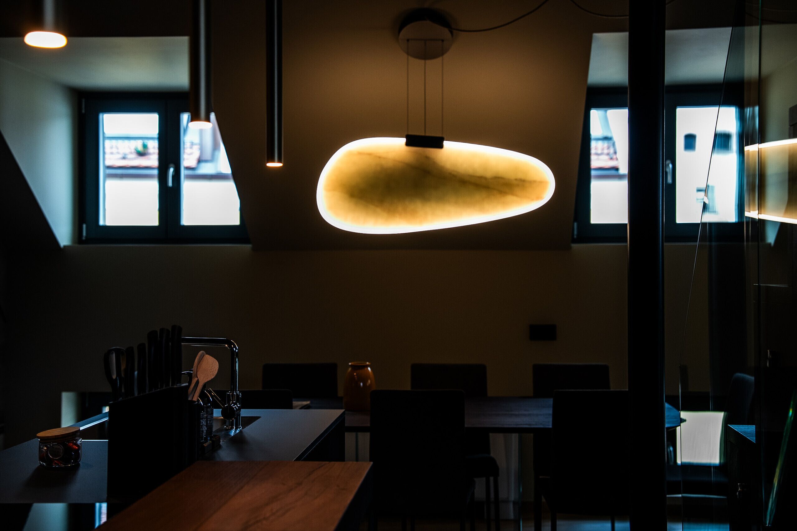 A modern dining area with a wooden table, chairs, and a pendant light.