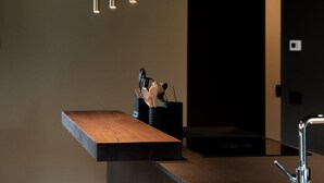 Een moderne keuken met een houten aanrechtblad, roestvrijstalen apparatuur en hanglampen.