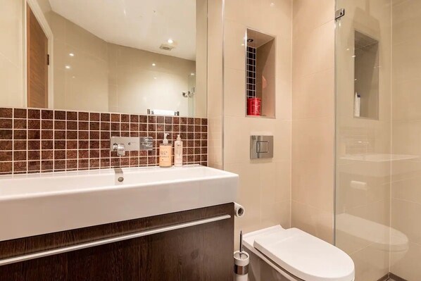 A modern bathroom with a white sink, dark wood vanity, and a glass shower enclosure.