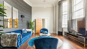 Una sala de estar moderna con un sofá azul, una mesa redonda para café y un televisor.