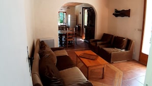 A spacious living room with a wooden ceiling, a sofa set, a coffee table, and a fireplace.