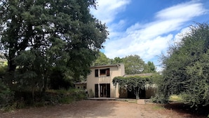 A two-story building with a dirt driveway and surrounding greenery.