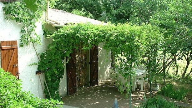 A rustic building with a covered porch, a wooden door, and a small table.