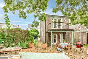 A wooden house with a balcony, a barbecue area, and outdoor seating. - Charming Sag Harbor Apartment. Two blocks from Main and Bay Streets. (Sag Harbor)