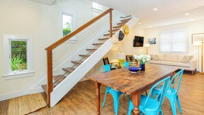 A dining area with a wooden table, blue chairs, and a staircase with wooden railings. - Charming Sag Harbor Apartment. Two blocks from Main and Bay Streets. (Sag Harbor)