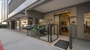 A modern building with a glass entrance labeled "AQUA TOWERS". - Apart With Barbecue 600m From the Beach Aqt0604 (Itapema)