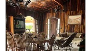 A rustic dining area with wooden chairs, a round table, and a television. - Beautiful farm in Igarata right on the dam. (Canto das Águas Igaratá)