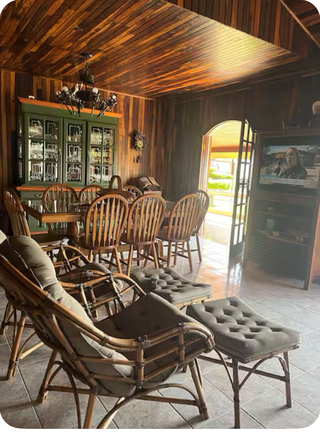 A cozy room with a wooden ceiling, a dining table with chairs, and a television.
