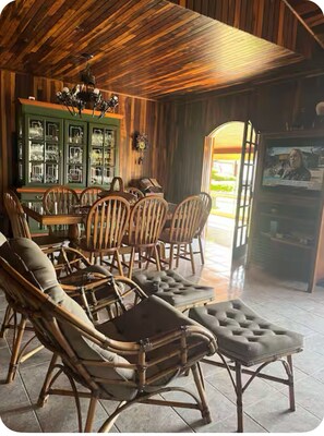A cozy room with a wooden ceiling, a dining table with chairs, and a television. - Beautiful farm in Igarata right on the dam. (Canto das Águas Igaratá)