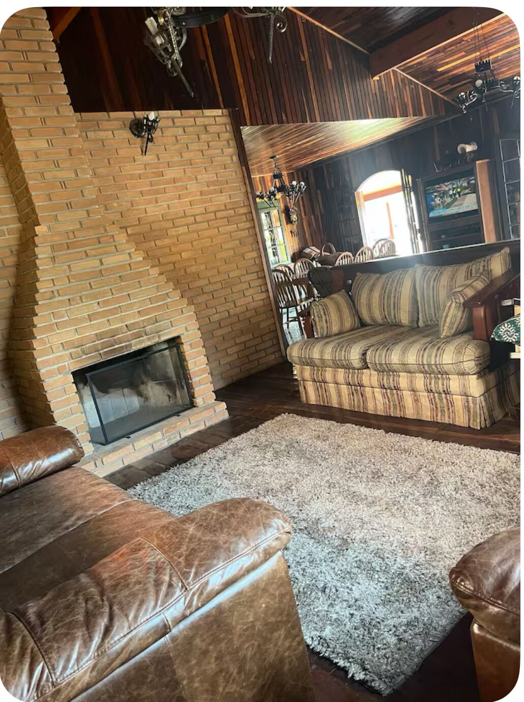 Una sala de estar acogedora con chimenea de ladrillo, sofás de cuero y un tapiz estampado.