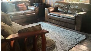 A cozy living room with leather sofas, a wooden ceiling, and large windows. - Beautiful farm in Igarata right on the dam. (Canto das Águas Igaratá)