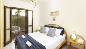 A neatly arranged bedroom with a bed, bedside tables, and a view through a door to an outdoor area.