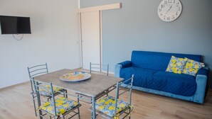 A room with a dining table, chairs, a blue sofa, and a wall clock. - Villa Rosy - Your Villa Near the Sea (Marina di Butera)