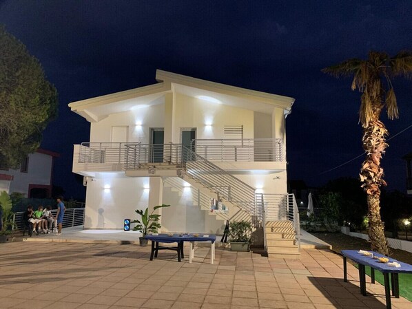 A two-story building with a balcony, a staircase, and outdoor seating.