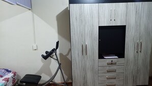A bedroom with a bed, a wooden wardrobe, and an exercise bike. - Apartment in Encarnación (WRC 2025) (Encarnación)