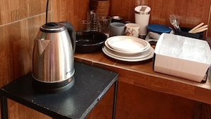 A kitchen with a kettle on a small table, a power outlet, a wooden cabinet, and various kitchen items. - Apartment in Encarnación (WRC 2025) (Encarnación)