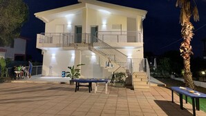 Ein zweistöckiges Gebäude mit Balkon, Treppe und Außenbereich zum Sitzen.