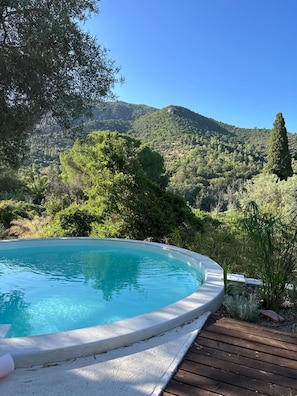 A swimming pool with a wooden deck and a mountain backdrop. - Borgo Ferraria - Sinnai (Sinnai)