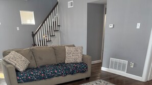 A living room with a beige sofa, patterned throw blanket, and a large area rug. - 3-bedroom house in fabulous St. Louis with AC (St. Louis)