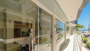 A modern building with large glass windows, a clear view of the street, and a sign indicating a parking area. - Seaview apt w/ BBQ 50m From Beach Att0602 (Itapema)