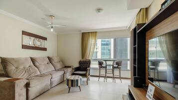A living room with a sofa, ottoman, armchair, and a dining area with chairs and a table.
