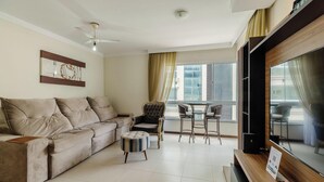 A living room with a sofa, armchair, ottoman, and a TV. - Seaview apt w/ BBQ 50m From Beach Att0602 (Itapema)