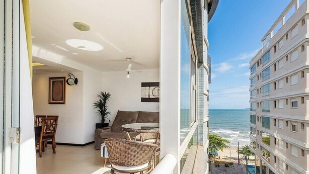 A balcony with a view of the ocean, a dining area with wicker furniture, and a ceiling fan. - Seaview apt w/ BBQ 50m From Beach Att0602 (Itapema)
