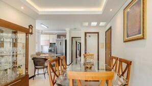 A dining area with a glass table, wooden chairs, a glass cabinet with wine glasses, and a framed quote on the wall. - Seaview apt w/ BBQ 50m From Beach Att0602 (Itapema)