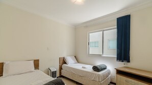 Une chambre avec deux lits, un radiateur, une commode et une fenêtre avec des rideaux.