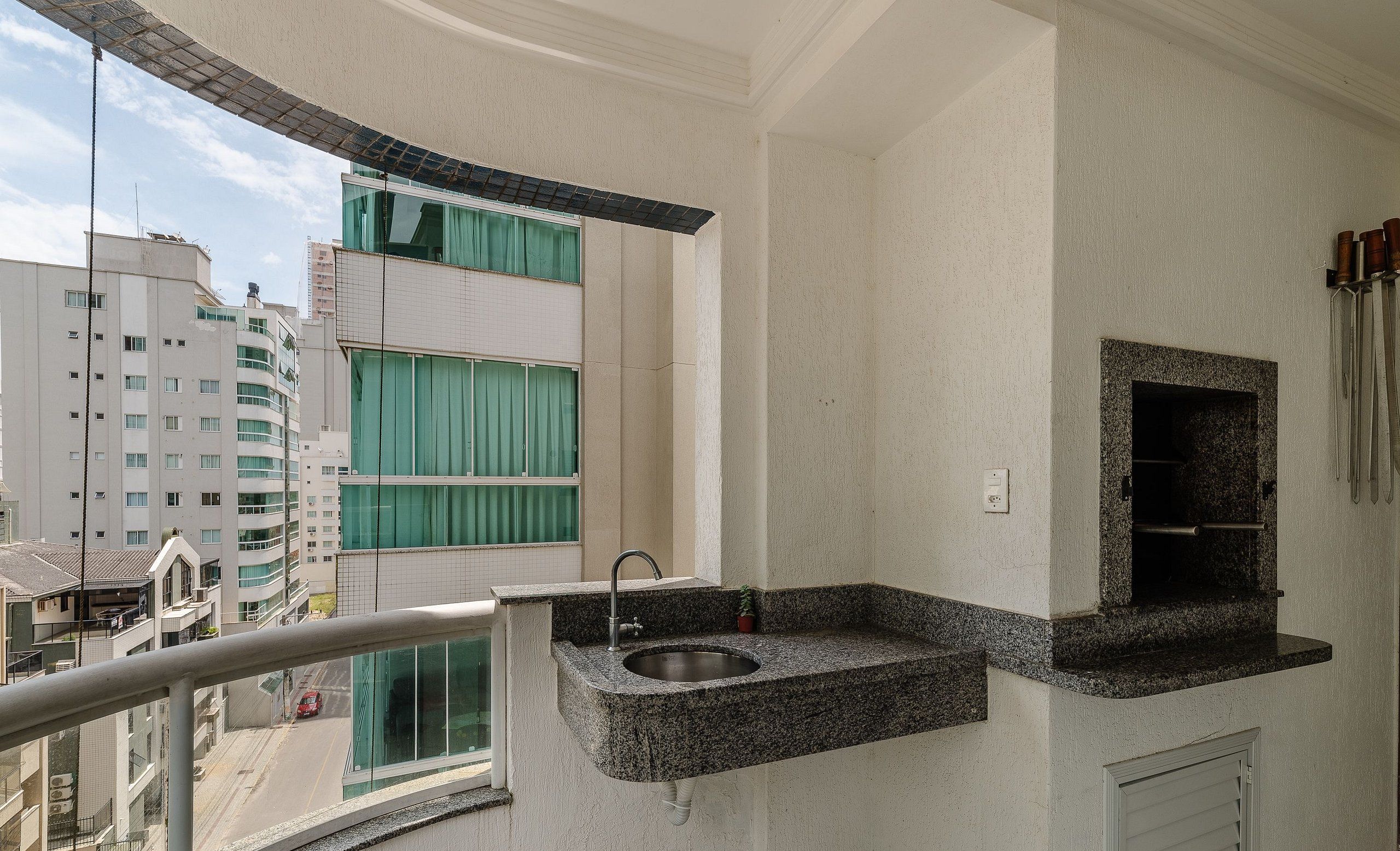 Een balkon met een granieten spoelbak, een raam met gordijnen en uitzicht op een stadsbeeld.