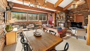 A rustic interior with a stone fireplace, wooden beams, and a dining area.