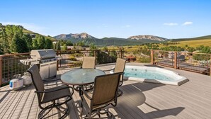 A deck with a hot tub, barbecue grill, and outdoor seating.
