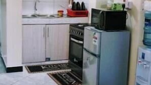Een kleine keuken met witte kastjes, een koelkast en een magnetron.