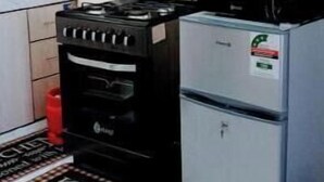Een kleine keuken met een gasfornuis, een koelkast en een magnetron.