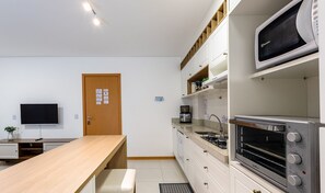 Eine kleine Küche mit Holztisch, Mikrowelle, Toaster und Kaffeemaschine.