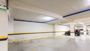 A parking garage with white walls, blue and yellow painted lines, and numbered parking spaces. - Modern apt With Pool Near the Beach Avr0203 (Penha)