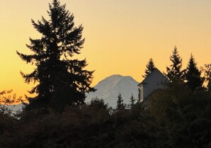 Une montagne au coucher du soleil, avec une maison au premier plan.